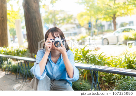 A woman holding a camera 107325090