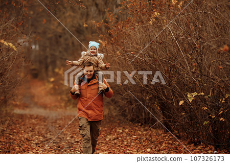 Happy family father and child daughter on a walk in the autumn leaf fall in park Happy family father and child daughter on a walk in the autumn leaf fall in park 107326173