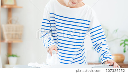 微笑的女人在客廳熨衣服 107326252