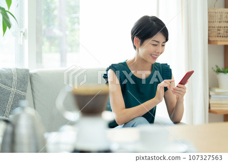 A woman who operates a smartphone in the living room 107327563