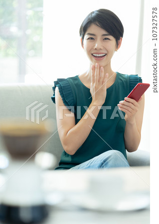 A woman who operates a smartphone in the living room A woman who operates a smartphone in the living room 107327578