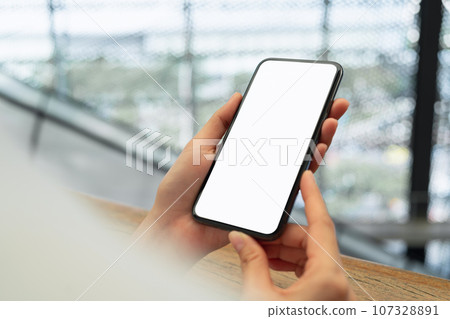 Hand holding black smartphone with blank screen for graphic display montage at shopping mall. 107328891