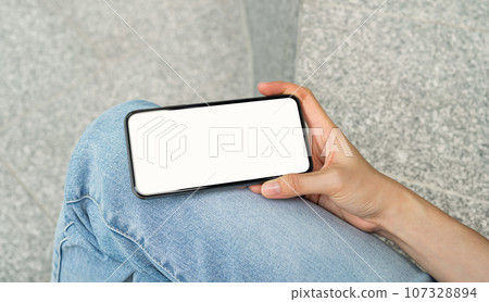 Hand holding black smartphone with blank screen for graphic display montage at shopping mall. 107328894