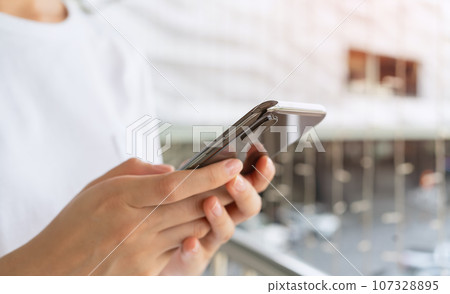 Woman's hands holding smartphone and using a social media at night street. 107328895