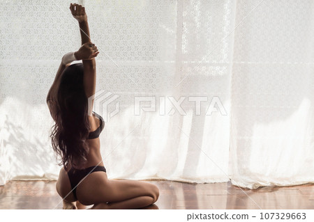 sexy woman in black bra and pant stretching arm exercise by window sexy woman in black bra and pant stretching arm exercise by window 107329663