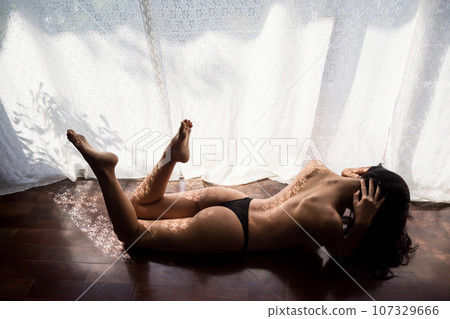 Topless Asian woman lying on wood floor to get tan by sunbath Topless Asian woman lying on wood floor to get tan by sunbath 107329666