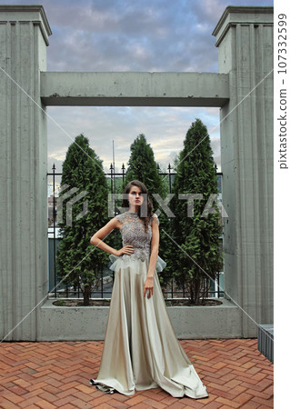 Fashion portrait of attractive woman standing in mansion yard Fashion portrait of attractive woman standing in mansion yard 107332599