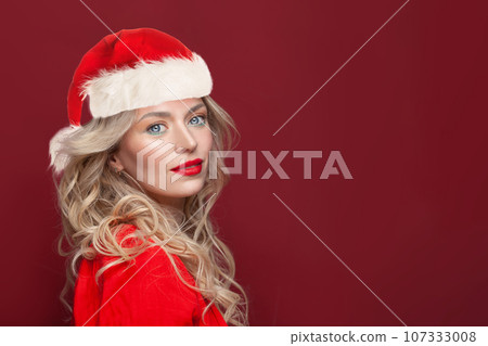 Cheerful young blonde woman Santa on red background 107333008
