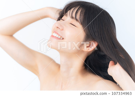 A middle-aged woman doing skin care against a white background 107334963