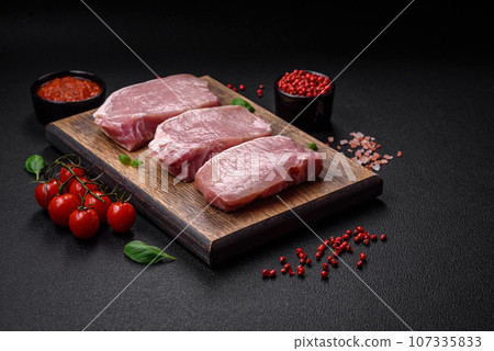 Raw fresh pork meat steak with salt, spices and herbs Raw fresh pork meat steak with salt, spices and herbs 107335833