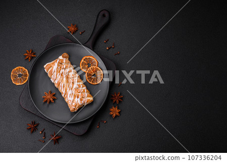 Delicious crispy braided bun with raisins inside and white icing outside 107336204