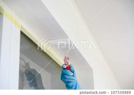 Worker painting on surface wall with paint roller brush. Worker painting on surface wall with paint roller brush. 107338989