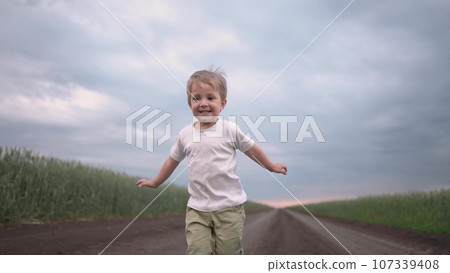 boy child running in nature in the park. happy family kid dream concept. free child son runs along a rural road next to a field in nature. free baby runs and lifestyle plays in the park 107339408