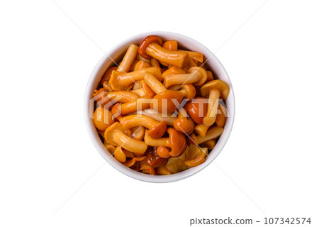 Delicious pickled honey mushrooms with salt and spices in a ceramic plate 107342574