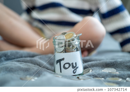 A glass bottle with the word toy on it. and silver coins for savings in a glass full 107342714