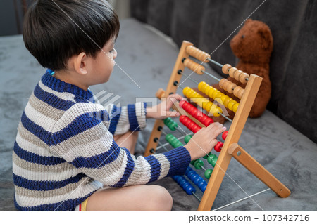 Asian boy playing with toys on the bed Asian boy playing with toys on the bed 107342716