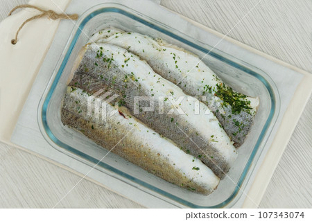 Marinated hake on a ceramic board on white background. Ready to cooking. Hake Filet. Top view. Marinated hake on a ceramic board on white background. Ready to cooking. Hake Filet. Top view. 107343074