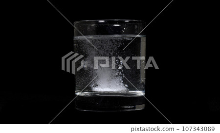 Slow motion footage of medicine melting in glass on black background. 107343089