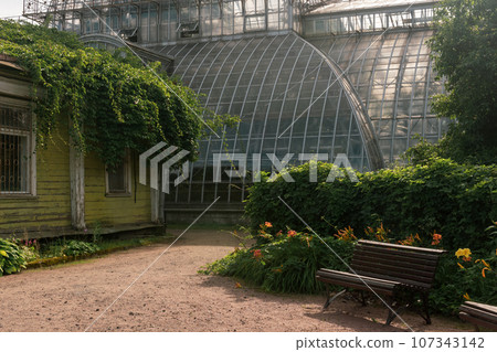 corner of an old botanical garden with a huge vintage greenhouse in the background 107343142