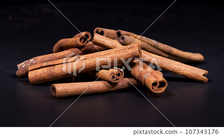 Close-up footage of cinnamon sticks on black background. 107343176