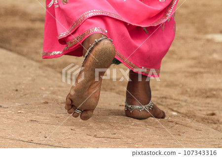 Indian woman walking barefoot with anklets on her feet. 107343316