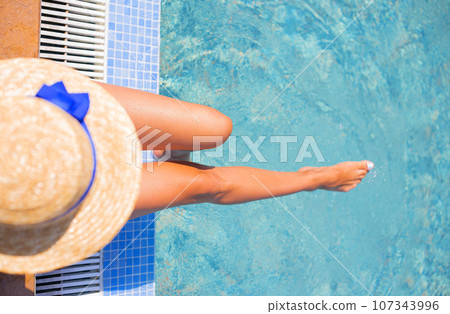 Beautiful girl in a hat near a blue pool - sun, summer, heat Beautiful girl in a hat near a blue pool - sun, summer, heat 107343996