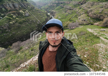 bearded Caucasian male traveler takes a selfie on smartphone against background of Aksu Canyon in Kazakhstan in spring bearded Caucasian male traveler takes a selfie on smartphone against background of Aksu Canyon in Kazakhstan in spring 107344546