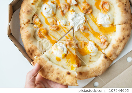 In your hands is a piece of juicy hot pizza. Italian pizza with seafood, shrimp and a lot of cheese. Home delivery, fast food. 107344695