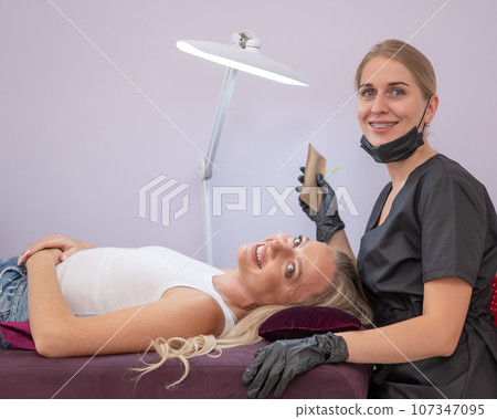 Caucasian woman on eyelash extension procedure.  Caucasian woman on eyelash extension procedure.  107347095