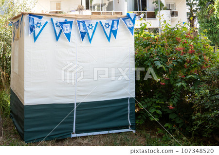 Sukkah in a yard of a residential building in Israeli town during Jewish holiday Sukkot Sukkah in a yard of a residential building in Israeli town during Jewish holiday Sukkot 107348520