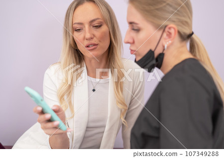 A woman shows the desired result to the master on a smartphone.  107349288