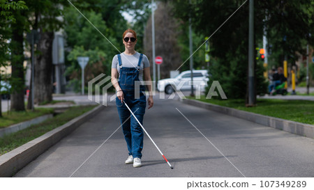 Blind pregnant woman walking down the street with a cane. Blind pregnant woman walking down the street with a cane. 107349289