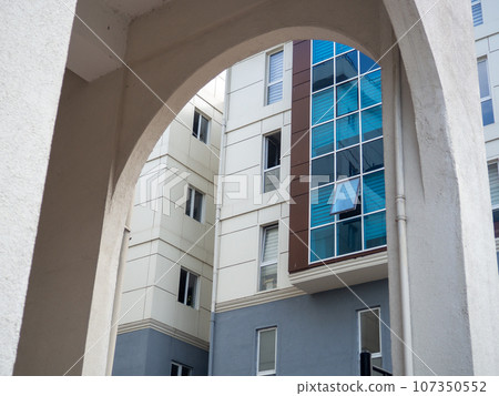 Arch and glazed windows. Modern urban architecture. High building from an unusual angle Arch and glazed windows. Modern urban architecture. High building from an unusual angle 107350552