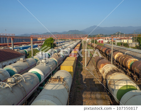 Railroad in the city against the backdrop of mountains.. Many railway paths. Wagons and trains on the tracks. unloading station. Tank wagons. Railroad in the city against the backdrop of mountains.. Many railway paths. Wagons and trains on the tracks. unloading station. Tank wagons. 107350817