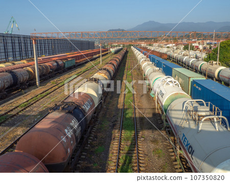 Railroad in the city against the backdrop of mountains.. Many railway paths. Wagons and trains on the tracks. Tank wagons. Railroad in the city against the backdrop of mountains.. Many railway paths. Wagons and trains on the tracks. Tank wagons. 107350820