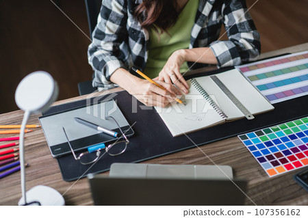 Female artist designer drawing logo in paper and working about graphic design in creativity office 107356162