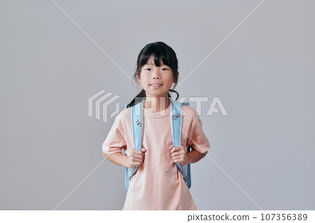 Elementary school girl standing with a school bag on her back 107356389