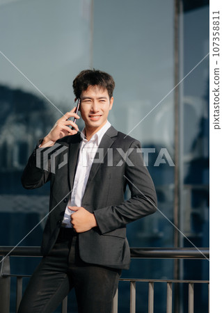 Young Asian business man working at outside business center with laptop, tablet, smartphone  and taking notes on the paper. 107358811