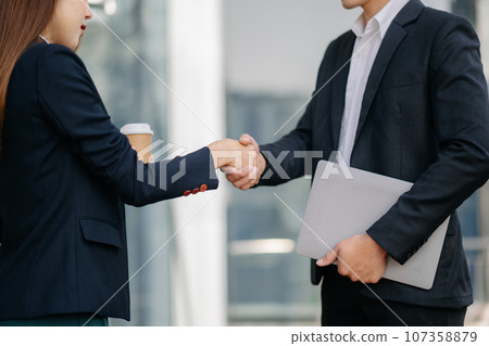 Business people shaking hands during a meeting. Two happy mature businessmen and woman Business people shaking hands during a meeting. Two happy mature businessmen and woman 107358879
