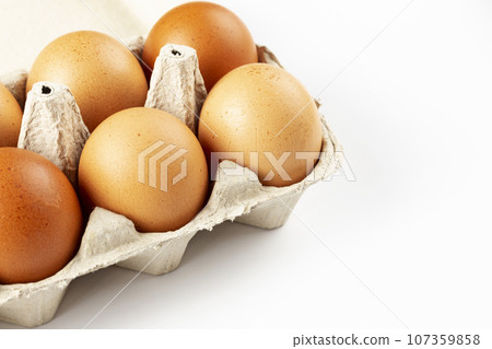 A tray of brown fresh hens eggs on white background. Eco-friendly egg production. A tray of brown fresh hens eggs on white background. Eco-friendly egg production. 107359858