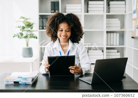 Business woman using tablet and laptop for doing math finance on an office desk, tax, report, accounting, statistics, and analytical research concept in office Business woman using tablet and laptop for doing math finance on an office desk, tax, report, accounting, statistics, and analytical research concept in office 107360652