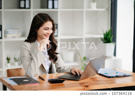 Business woman using tablet and laptop for doing math finance on an office desk, tax, report, accounting, statistics, and analytical research concept in office Business woman using tablet and laptop for doing math finance on an office desk, tax, report, accounting, statistics, and analytical research concept in office 107364116