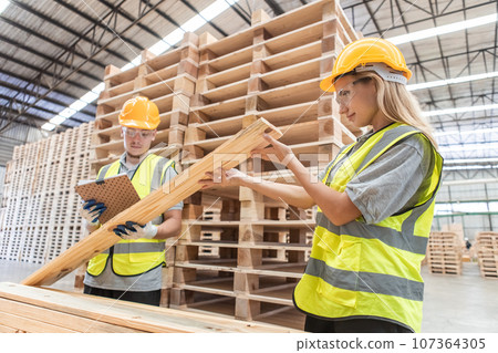 Team engineer carpenter wearing safety uniform and hard hat working holding clipboard Team engineer carpenter wearing safety uniform and hard hat working holding clipboard 107364305