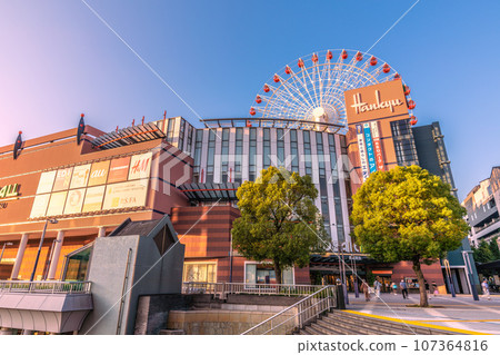 Yokohama cityscape, Japan, September. In front of Center Kita Station, view of the Ferris wheel and Tsuzuki Hankyu, etc., reflected in the blue sky and sunset Yokohama cityscape, Japan, September. In front of Center Kita Station, view of the Ferris wheel and Tsuzuki Hankyu, etc., reflected in the blue sky and sunset 107364816