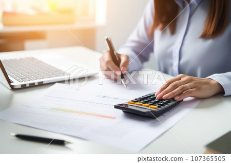 Closeup shot of businesswoman using a calculator and laptop in an office 107365505