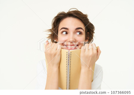 Portrait of happy woman with planner, holding notebook, reading notes and smiling, standing over white background Portrait of happy woman with planner, holding notebook, reading notes and smiling, standing over white background 107366095