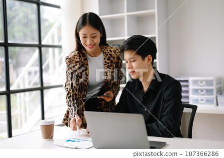 Two Asian business man and woman workers talking on the smartphone and using laptop Professionals in Teamwork Finance, Marketing, and Success Two Asian business man and woman workers talking on the smartphone and using laptop Professionals in Teamwork Finance, Marketing, and Success 107366286