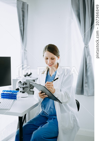 Caucasian smiling doctor or consultant sitting at a desk his neck biochemical samples, science chemical laboratory Caucasian smiling doctor or consultant sitting at a desk his neck biochemical samples, science chemical laboratory 107366849