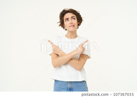 Thinking woman pointing sideways, looking up with thoughtful face, making decision, choosing, standing over white background 107367033