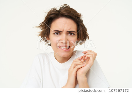 Portrait of woman jumps from fear, looks disgusted, cringe from something, express dislike or aversion, stands over white background Portrait of woman jumps from fear, looks disgusted, cringe from something, express dislike or aversion, stands over white background 107367172